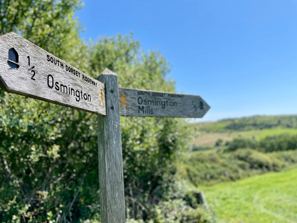A signpost indicating directions to Osmington and Osmington Mills at Woodbine Cottage Osmington