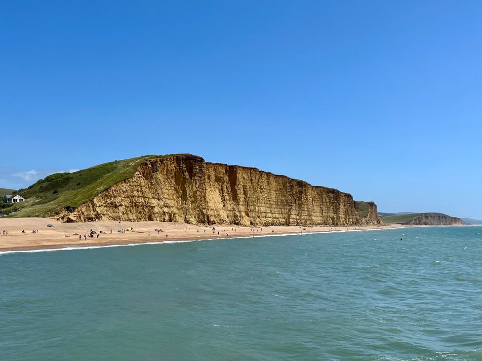 A beach with cliffs and people at Woodbine Cottage in Osmington