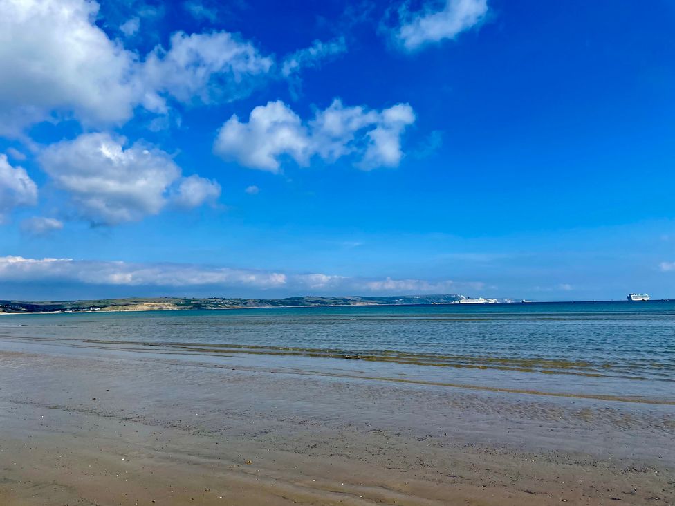 A beach with water and clouds at Woodbine Cottage in Osmington