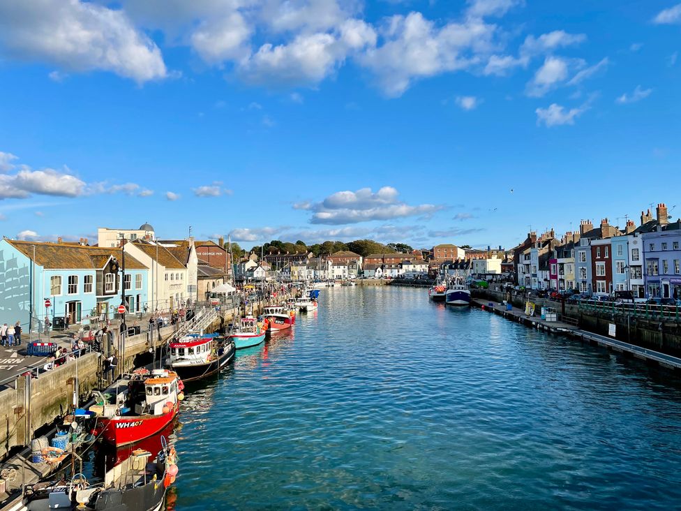A view of boats along a river with buildings at Woodbine Cottage in Osmington