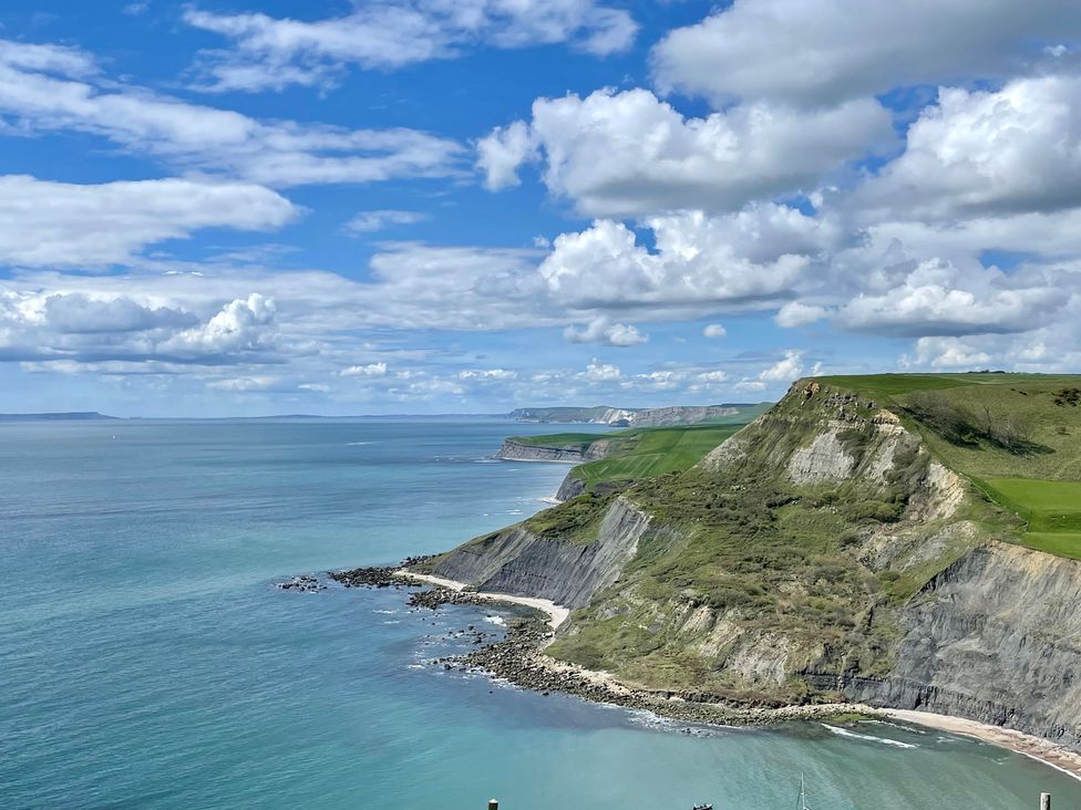 A view of cliffs and ocean under a cloudy sky at Woodbine Cottage in Osmington