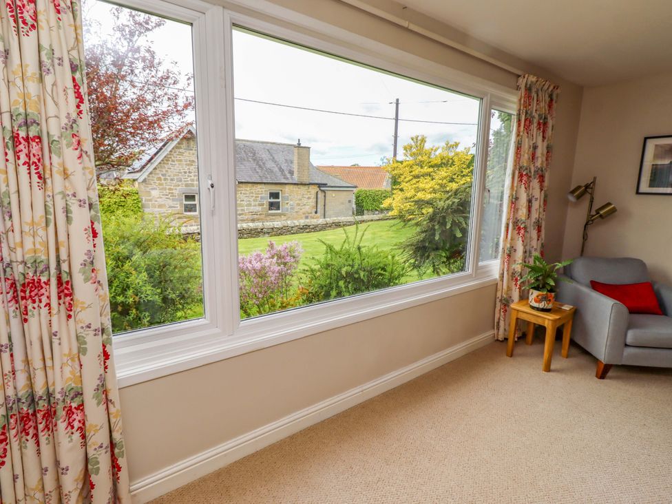A living room with a window overlooking a garden at Campden in Rennington near Embleton