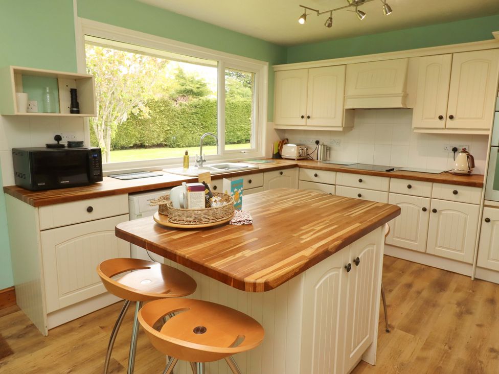 A kitchen with an island and stools at Campden in Rennington near Embleton