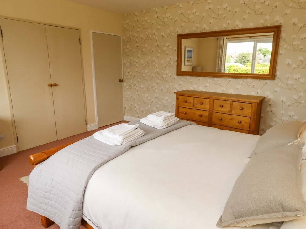 A bedroom with a bed and dresser at Campden in Rennington near Embleton