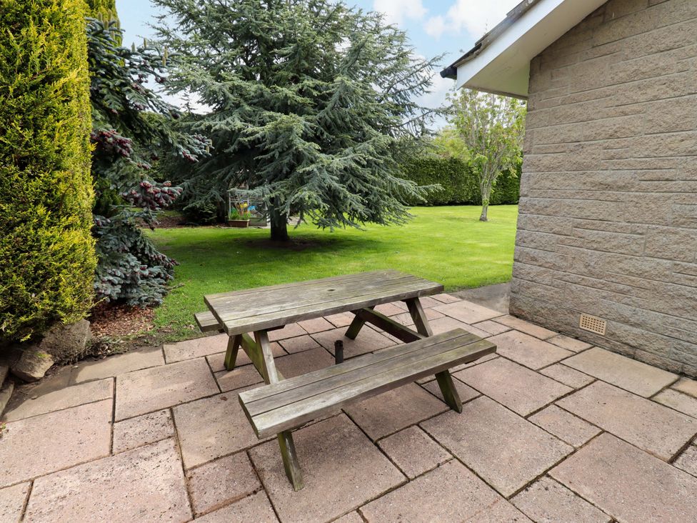 A garden with a wooden picnic table on a paved patio at Campden in Rennington near Embleton
