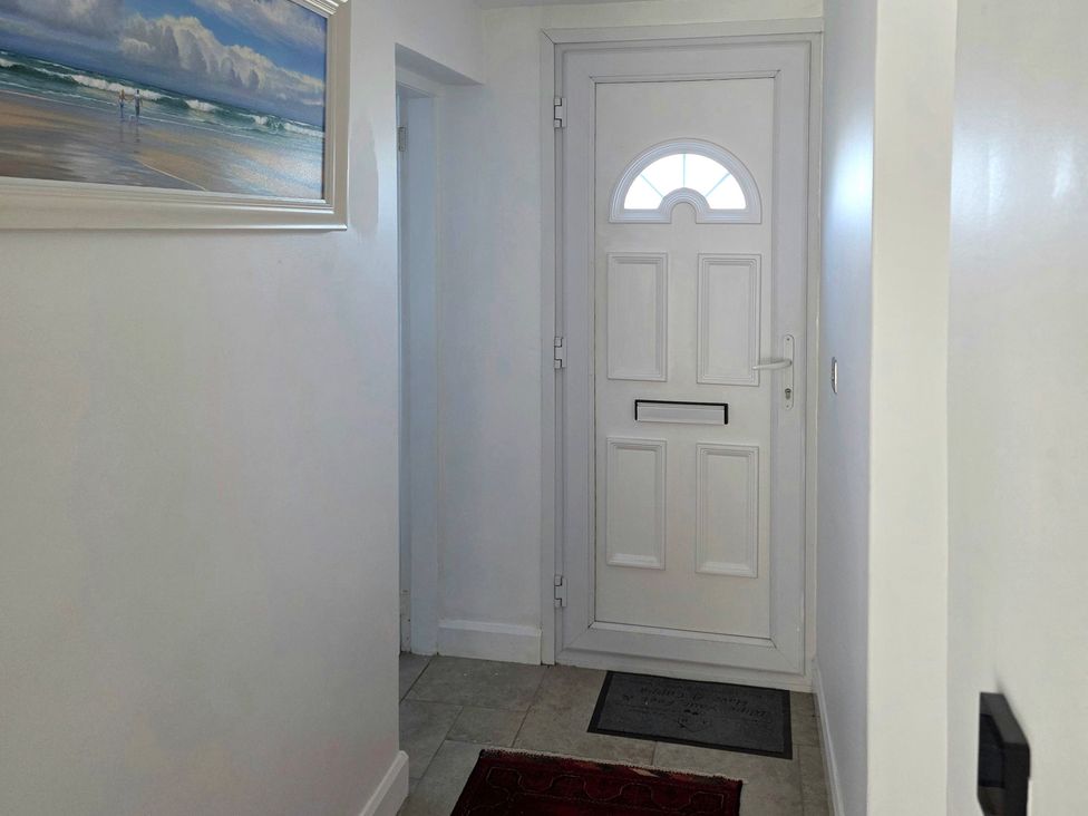 A hallway with a front door and wall painting at Pant in Holyhead