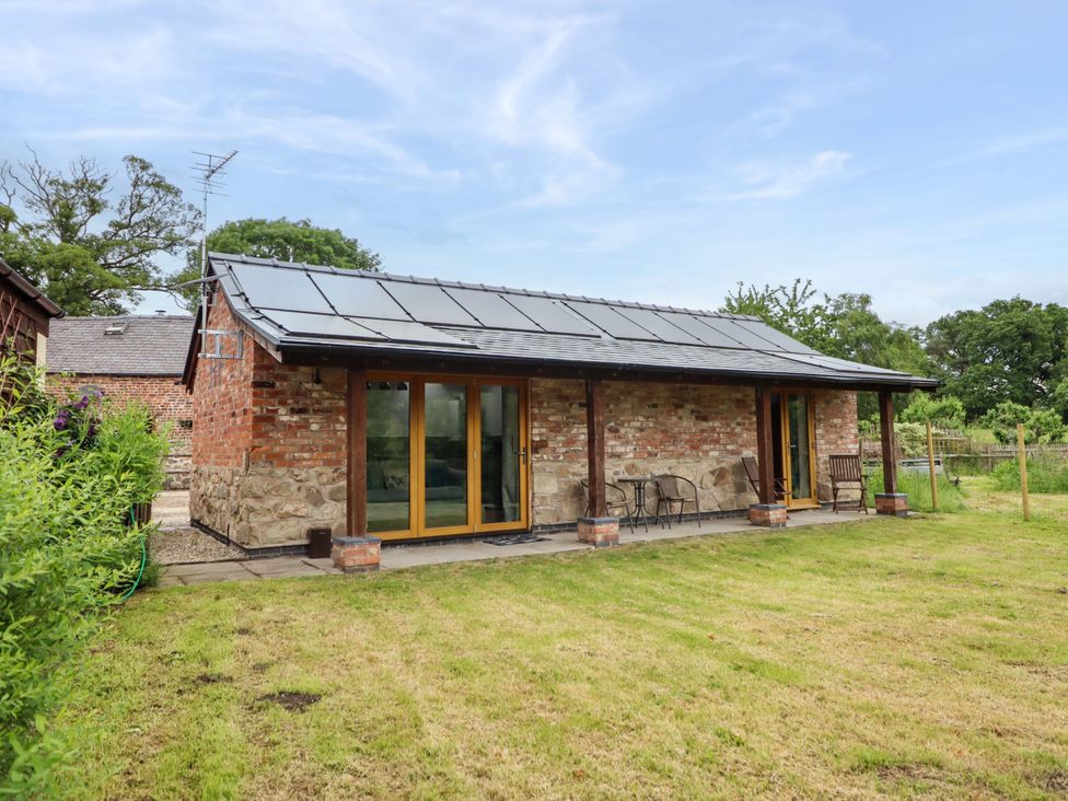 An outdoor area of a house with chairs and a table at Henlle Home Farm in Gobowen