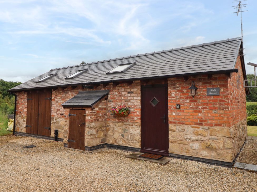 An exterior view of a brick building with a gravel path at Henlle Home Farm in Gobowen