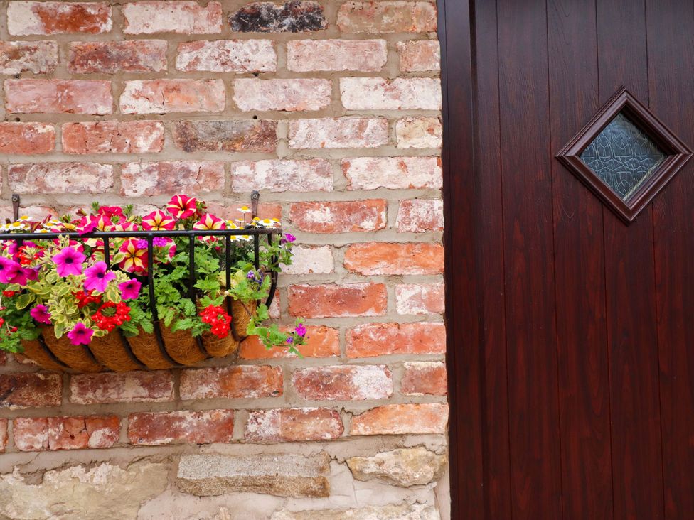 A door beside a flower planter on a brick wall at Henlle Home Farm in Gobowen