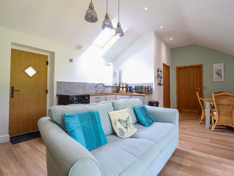 A living room with a sofa and kitchen area at Henlle Home Farm in Gobowen