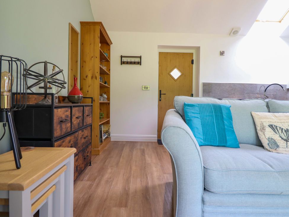 A living room with a sofa and bookshelf at Henlle Home Farm in Gobowen