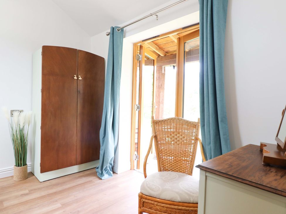 A room with a wardrobe, chair, and door at Henlle Home Farm Gobowen