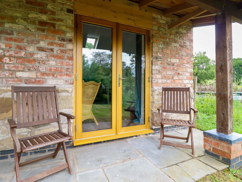 An outdoor area with wooden chairs and a door at Henlle Home Farm in Gobowen