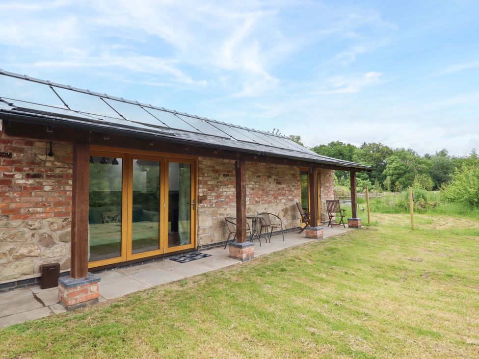 An outdoor area with glass doors and seating at Henlle Home Farm in Gobowen