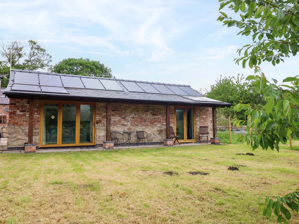 A house with patio chairs and large windows at Henlle Home Farm in Gobowen