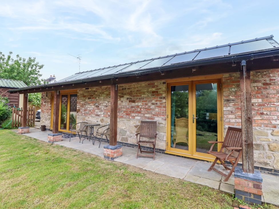 An outdoor patio with chairs and a brick wall at Henlle Home Farm in Gobowen