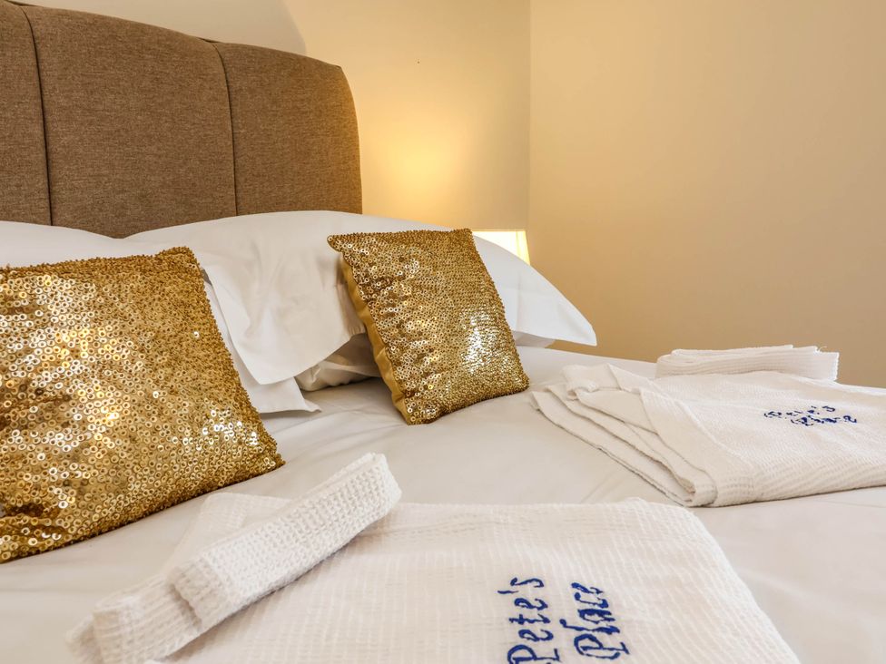 A bed with gold throw pillows and towels at Pete's Place in Taunton