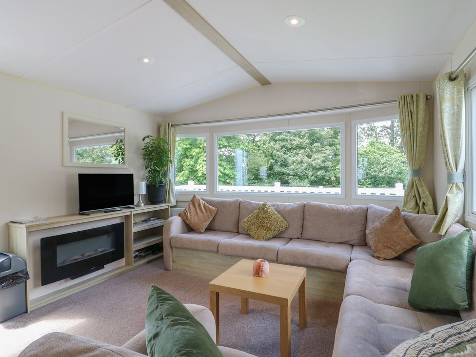 A living room with a sofa and television at Forest Retreat - FO26 in Saxmundham