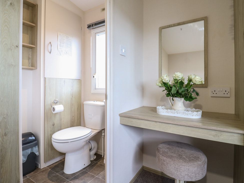 A bathroom with a toilet, sink, and a mirror at Forest Retreat - FO26 Saxmundham