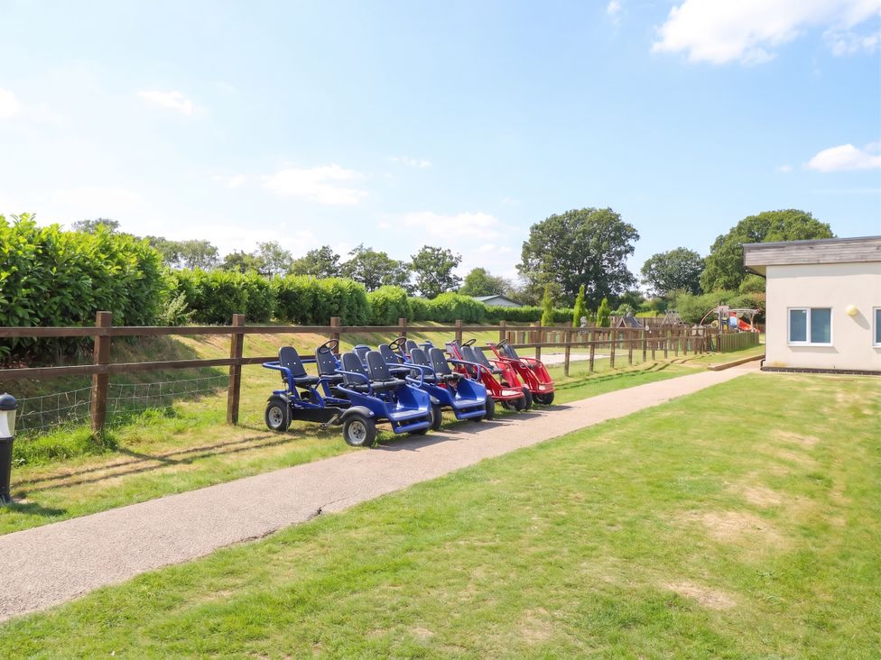 An outdoor area with go-karts parked along a pathway at Forest Retreat - FO26 Saxmundham
