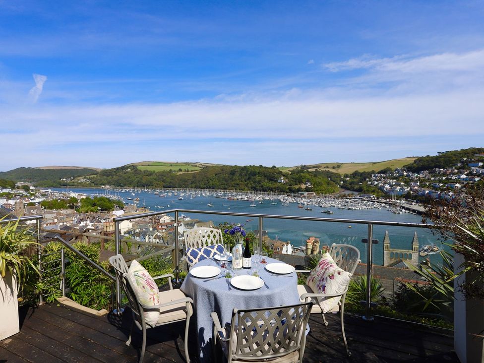 An outdoor dining area with a table and chairs overlooking the water at Dart Views in Dartmouth
