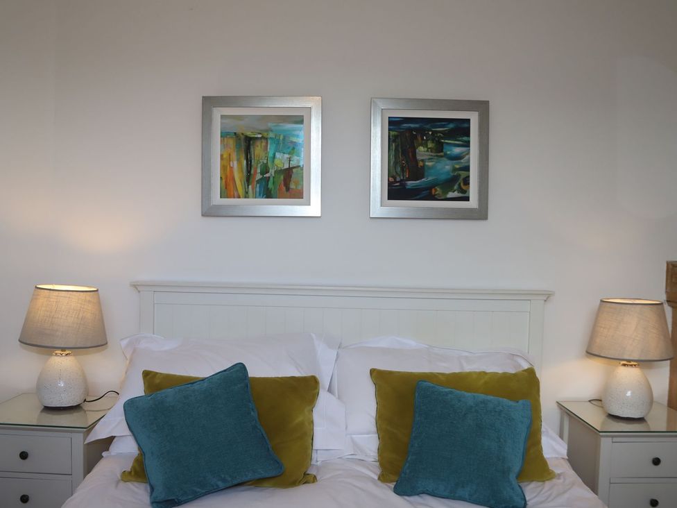 A bedroom with a bed, pillows, lamps, and wall art at Dart Views in Dartmouth