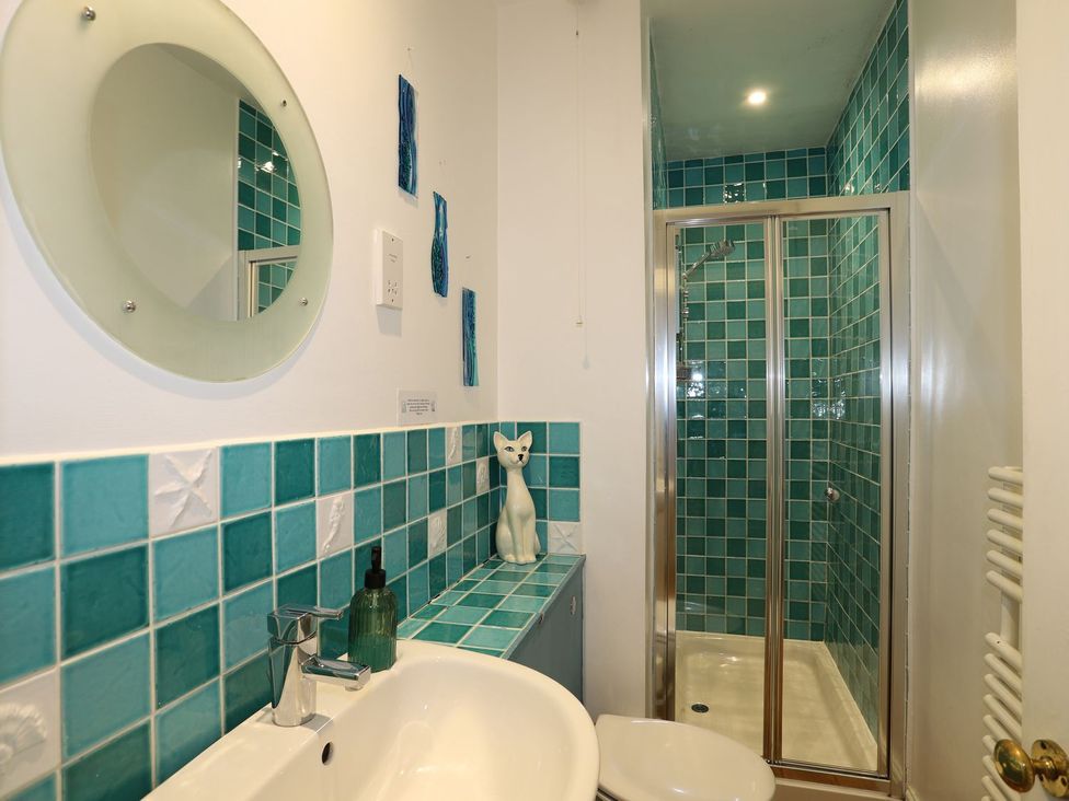 A bathroom with a basin, toilet, shower, and cat figurine at Dart Views in Dartmouth