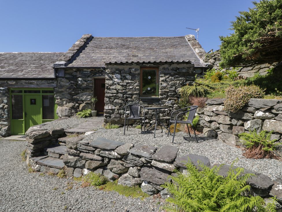 An outdoor seating area with a table and chairs at Beudy Bach Llanbedr