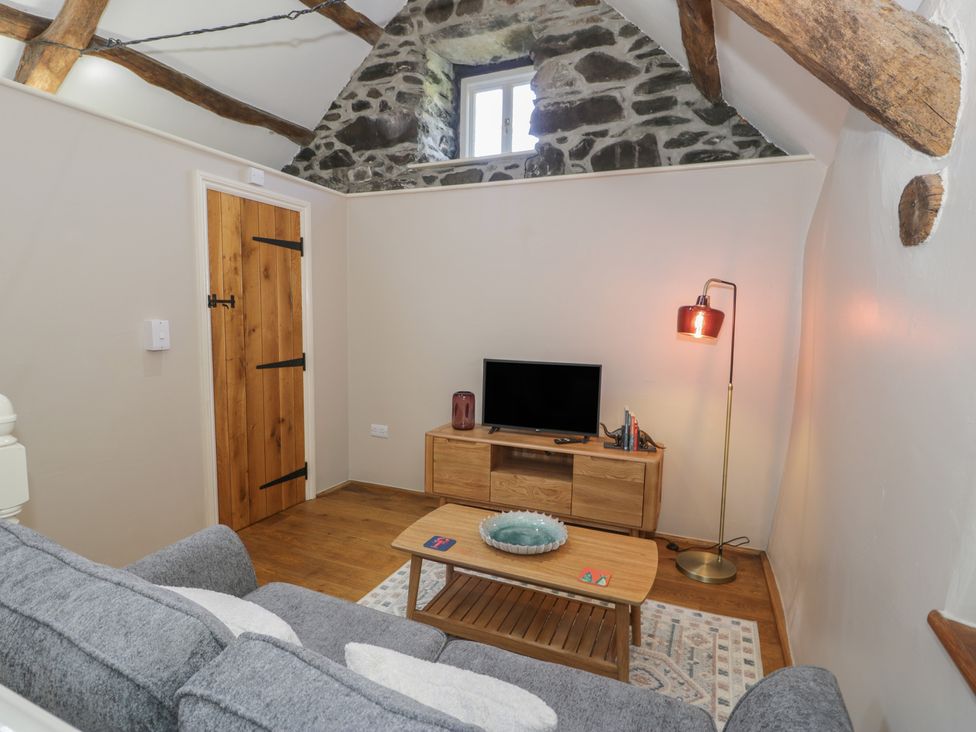 A snug with a sofa and television at Beudy Bach in Llanbedr