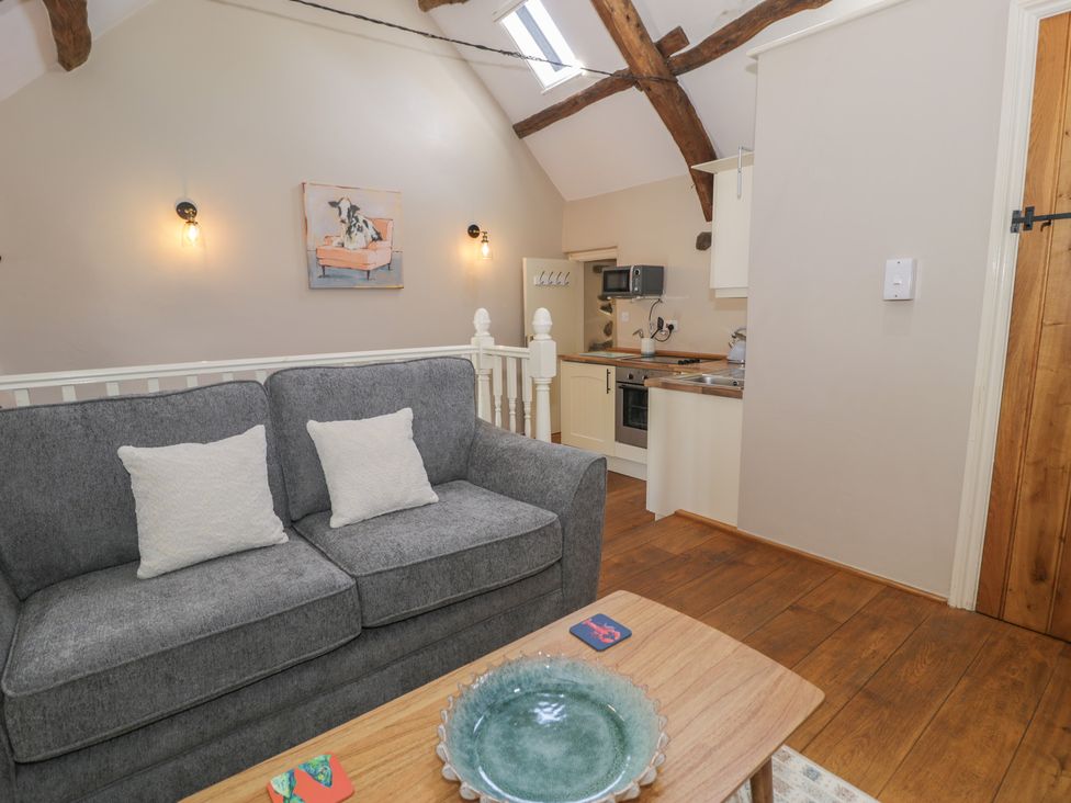 A living room with a sofa and kitchen area at Beudy Bach in Llanbedr