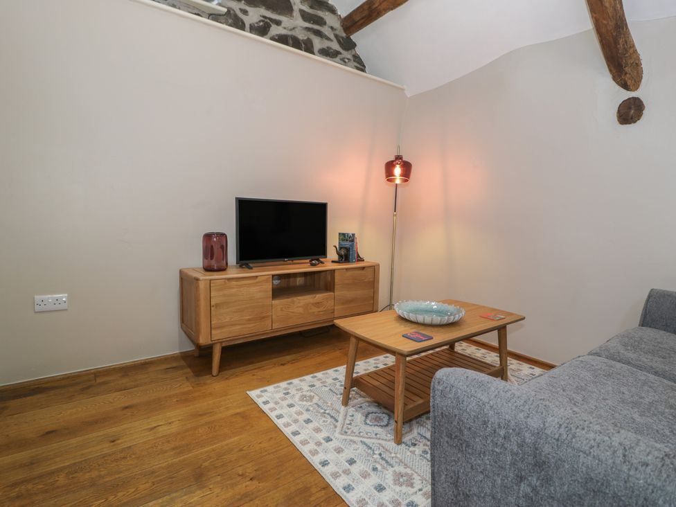 A living room with a television and a coffee table at Beudy Bach in Llanbedr