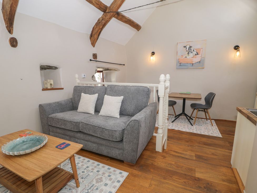 A living room with a sofa and dining area at Beudy Bach in Llanbedr