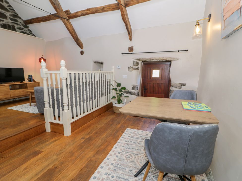 A living room with a sofa, table, and television at Beudy Bach in Llanbedr