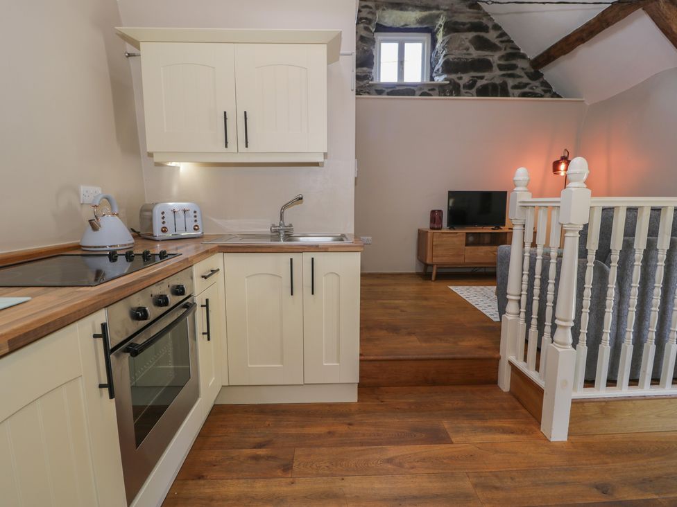 A kitchen with appliances and a staircase at Beudy Bach in Llanbedr