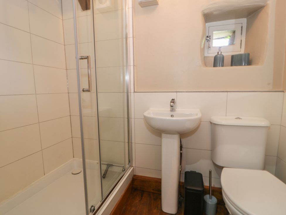 A bathroom with a shower, sink, and toilet at Beudy Bach, Llanbedr