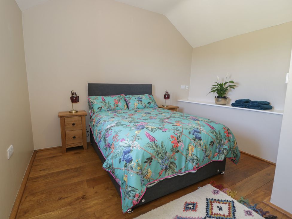 A bedroom with a bed and nightstand at Beudy Bach Llanbedr