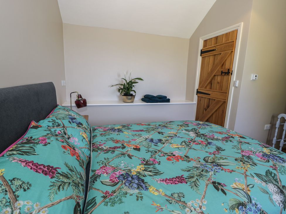 A bedroom with a bed, plant, towels and a door at Beudy Bach in Llanbedr