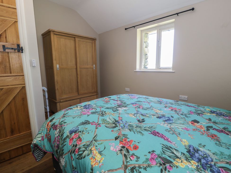 A bedroom with a bed and wardrobe at Beudy Bach in Llanbedr
