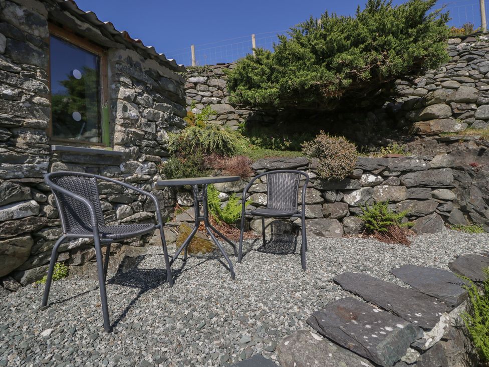 An outdoor seating area with a table and chairs at Beudy Bach Llanbedr