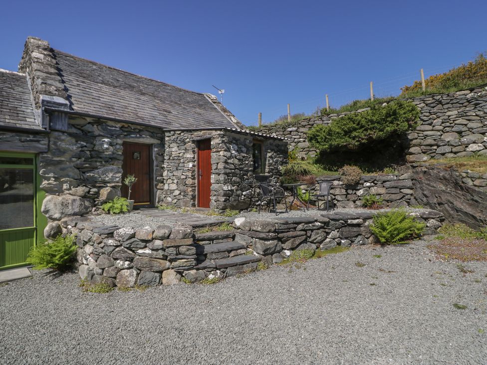 A stone building with doors and plants at Beudy Bach Llanbedr