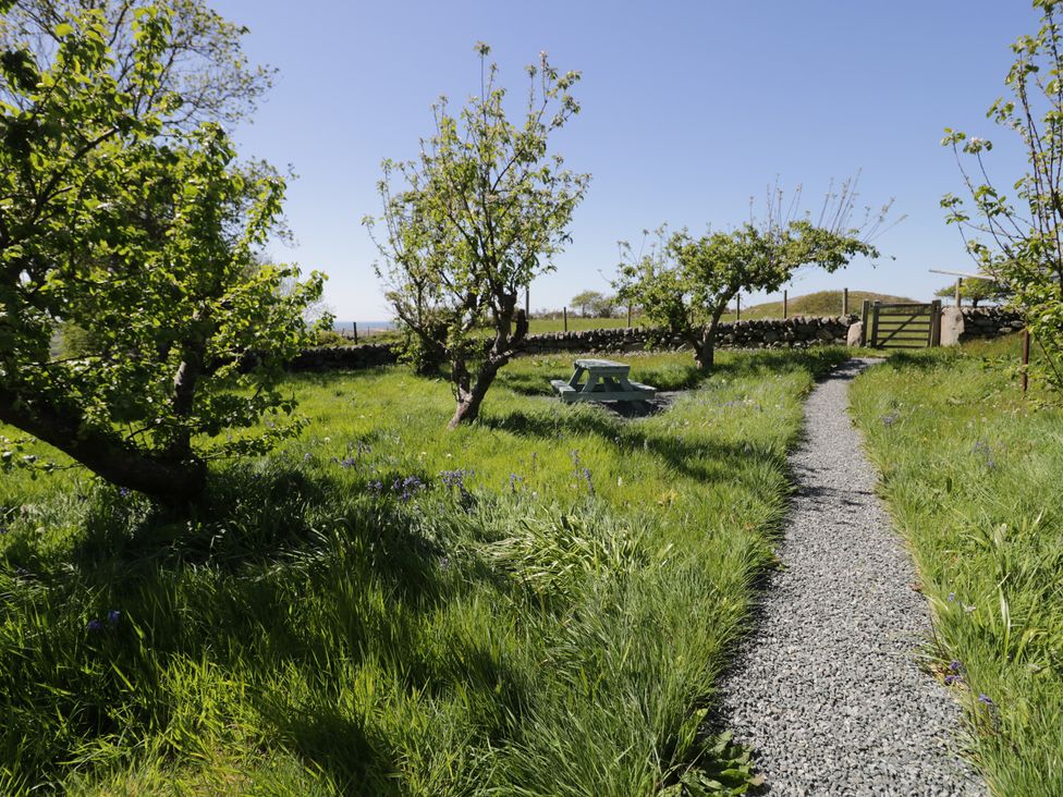 A garden with trees and a gravel path at Beudy Bach Llanbedr