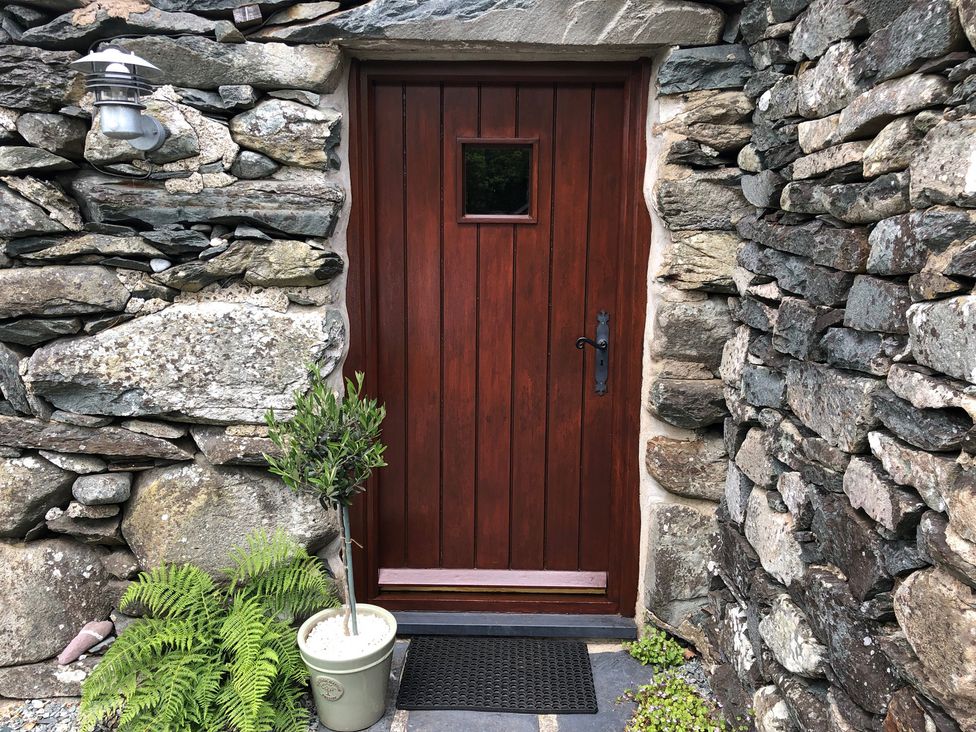 A door with a window and stone wall at Beudy Bach near Llanbedr