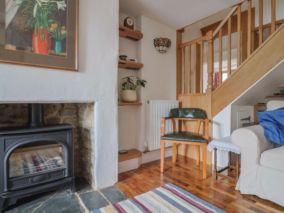 A living room with a stove and shelving at Saybrook Cottage in Charmouth