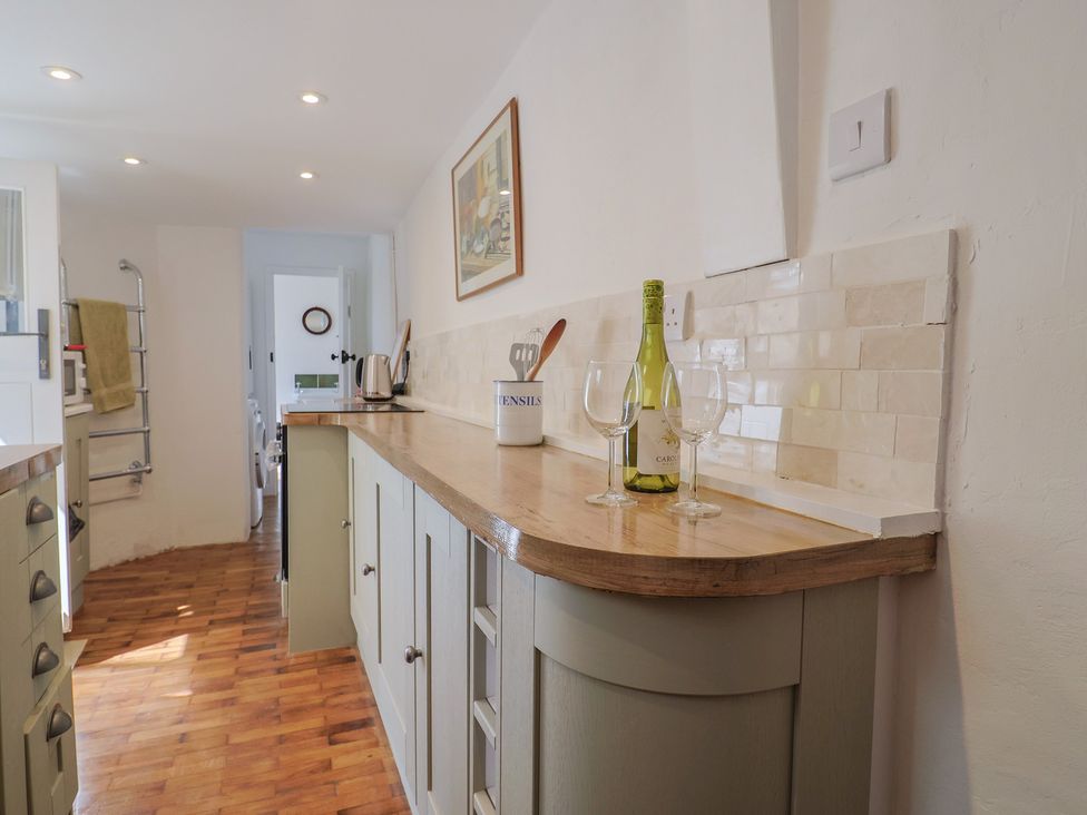 A kitchen with a counter and wine glasses at Saybrook Cottage in Charmouth
