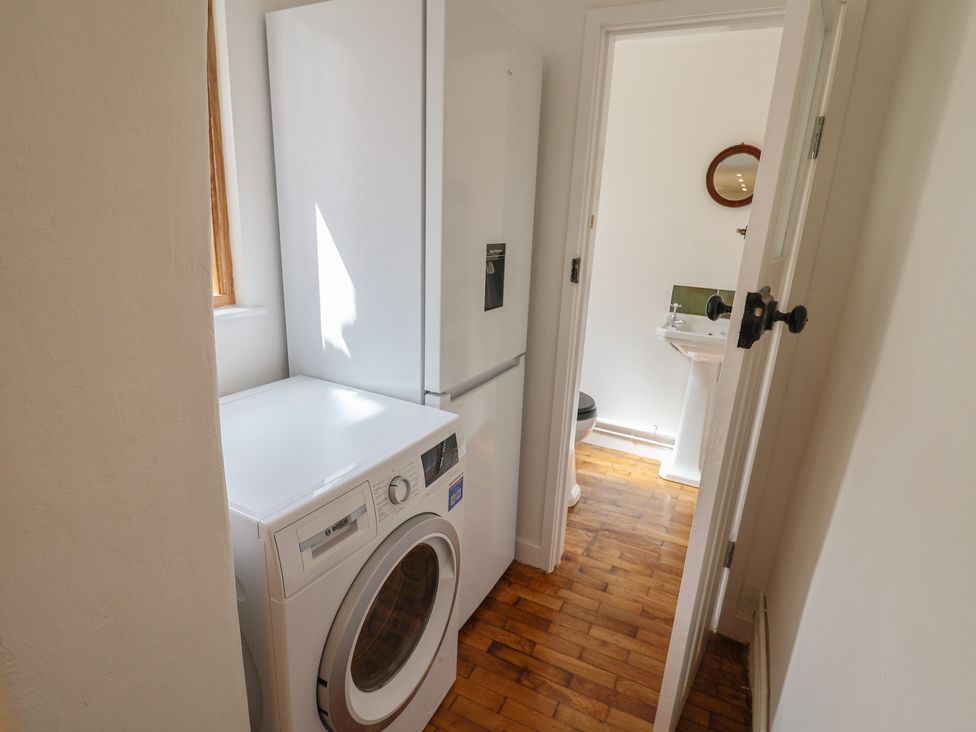 A laundry room featuring a washing machine and refrigerator at Saybrook Cottage in Charmouth