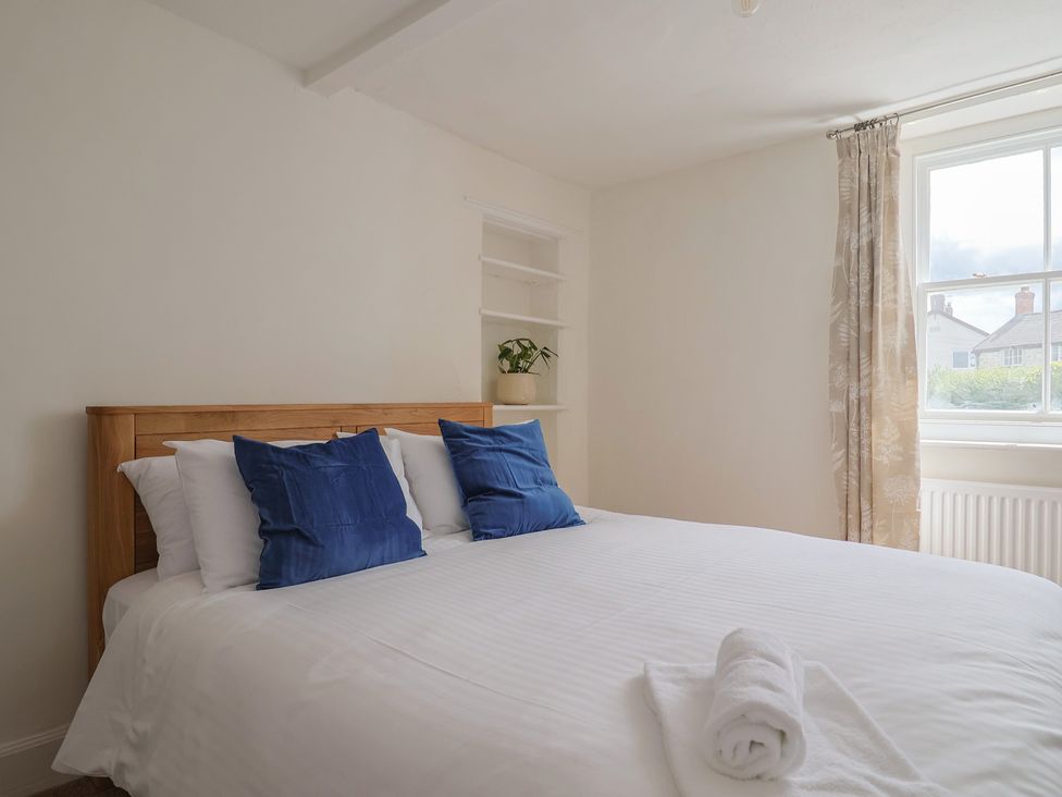 A bedroom with a bed and curtains at Saybrook Cottage in Charmouth