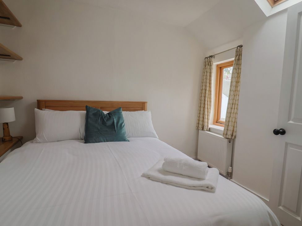 A bedroom with a bed and a window at Saybrook Cottage in Charmouth