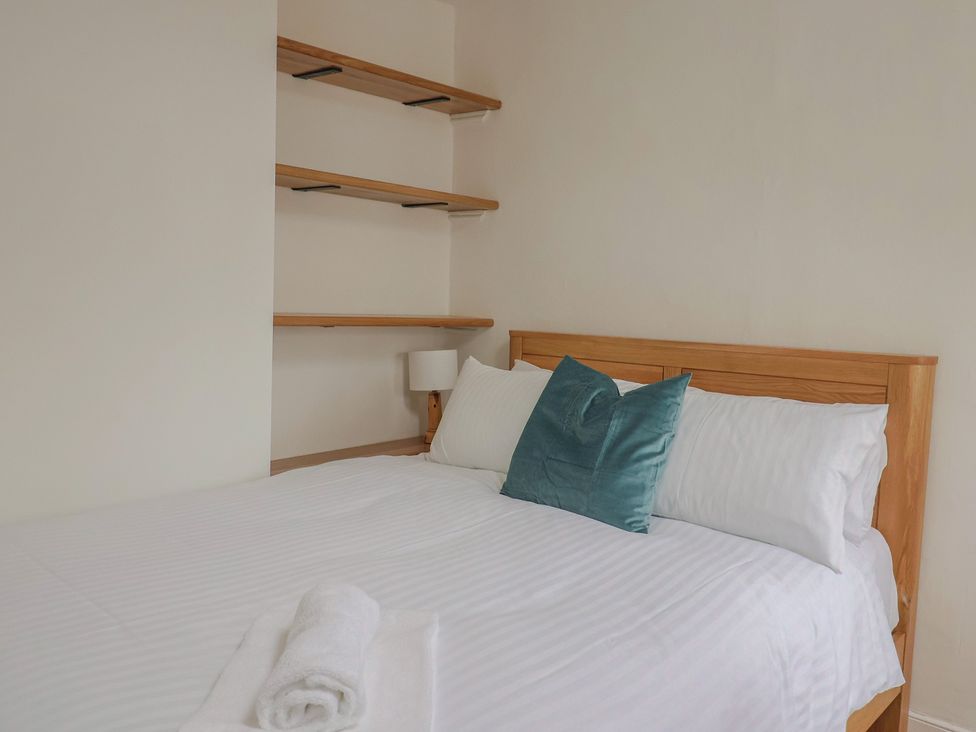 A bedroom with a bed and shelves at Saybrook Cottage in Charmouth