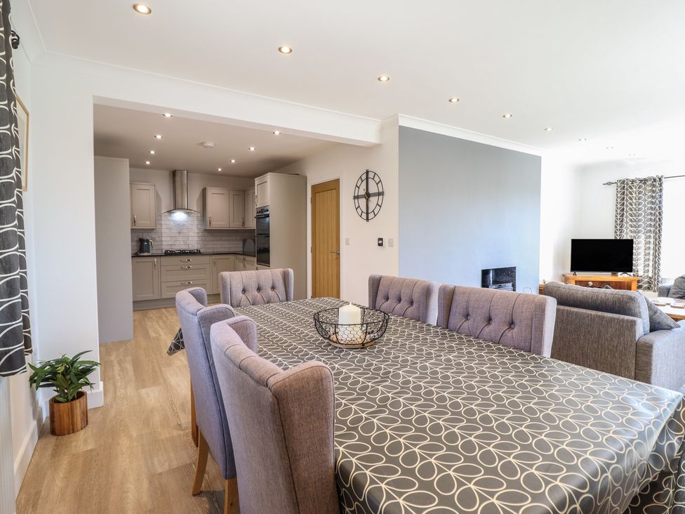 A dining room with a table and chairs adjacent to a kitchen at Tyn Y Weirglodd in Deiniolen
