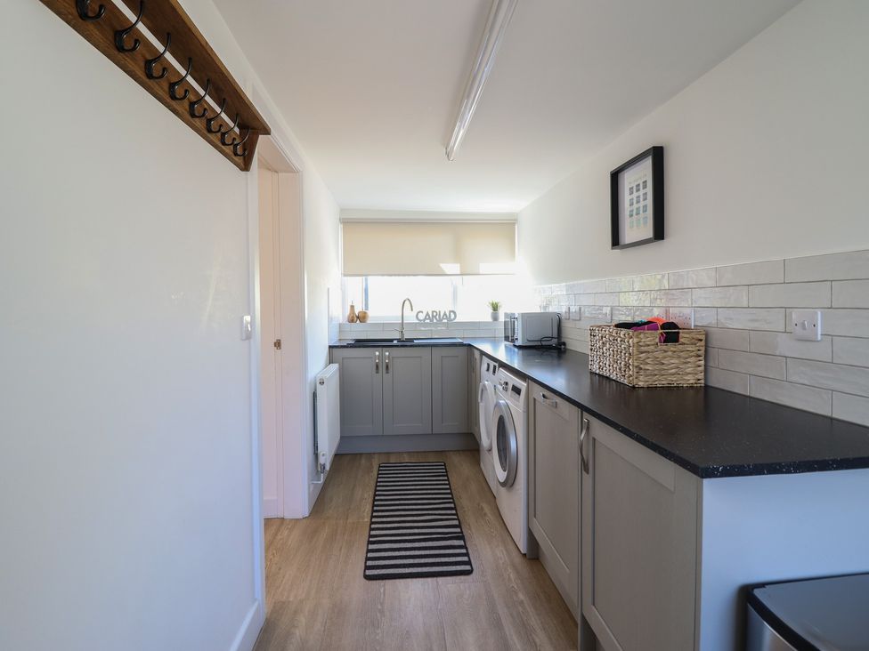 A utility room with a washing machine and microwave at Tyn Y Weirglodd in Deiniolen